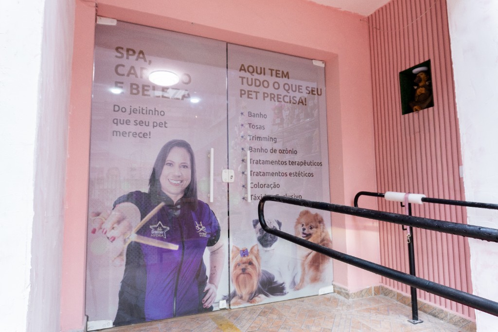 Porta de acesso a uma sala de spa e banho, com informações de serviços coladas no vidro.
