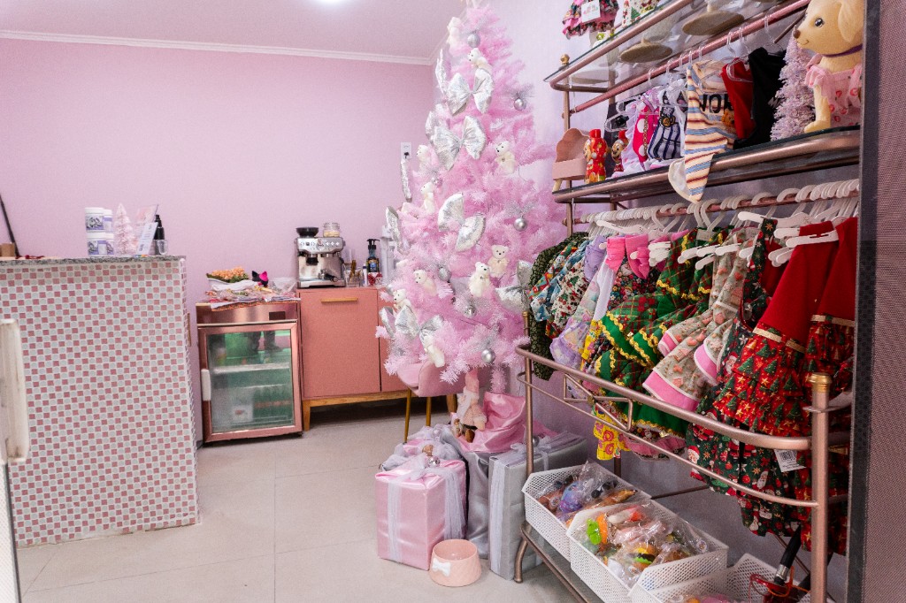 Estação de café e bebidas na recepção, com mini geladeira e prateleiras na parede.